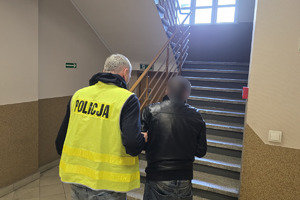 zdjęcie przedstawia policjanta stojącego z zatrzymanym