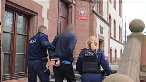 zdjęcie przedstawia policjantów prowadzących zatrzymanego