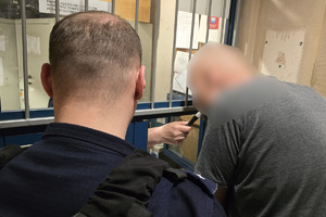 zdjęcie przedstawia mężczyznę w obecności policjanta, który jest badany alkomatem