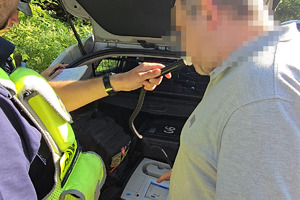 zdjęcie przedstawia policjanta badającego trzeźwość kierującego