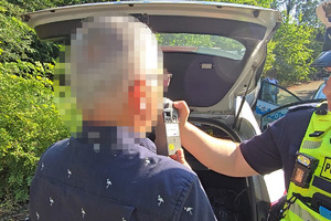 zdjęcie przedstawia policjanta badającego trzeźwość kierującego