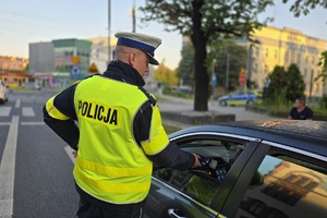 zdjęcie przedstawia policjanta kontrolującego trzeźwość kierującego