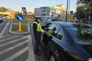 zdjęcie przedstawia policjanta kontrolującego trzeźwość kierującego
