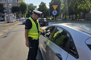 zdjęcie przedstawia policjanta kontrolującego trzeźwość kierującego