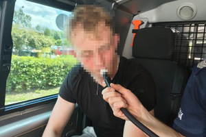 zdjęcie przedstawia ujętego kierującego w trakcie badania alkomatem