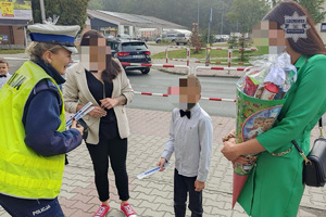 zdjęcie przedstawia policjanta rozdającego odblaski dzieciom