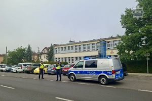 zdjęcie przedstawia policjanta rozdającego odblaski dzieciom