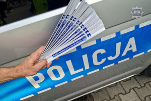 zdjęcie przedstawia policjanta rozdającego odblaski dzieciom