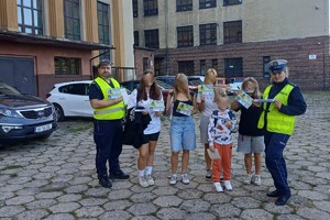 zdjęcie przedstawia policjantów rozdających dzieciom odblaski