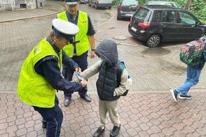zdjęcie przedstawia policjantów rozdających dzieciom odblaski