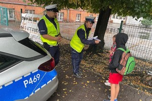 zdjęcie przedstawia policjantów rozdających dzieciom odblaski