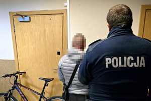 zdjęcie przedstawia policjanta z zatrzymanym. obok stoi rower