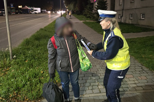 zdjęcie przedstawia policjantów wręczających elementy odblaskowe osobie