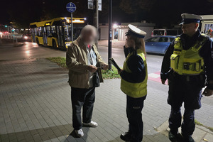 zdjęcie przedstawia policjantów wręczających elementy odblaskowe osobie