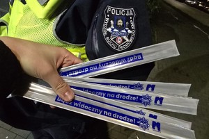 zdjęcie przedstawia policjantów wręczających elementy odblaskowe osobie