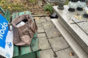 zdjęcie przedstawia torebkę damską leżącą bez opieki przy grobie