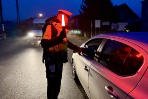 zdjęcie przedstawia policjanta w trakcie kontroli trzeźwości kierujących