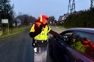 zdjęcie przedstawia policjanta w trakcie kontroli trzeźwości kierujących