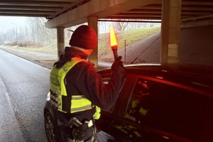 zdjęcie przedstawia policjanta w trakcie kontroli trzeźwości kierujących