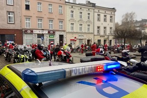 zdjęcie przedstawia policjantów zabezpieczających przejazd motocyklistów w strojach mikołajów
