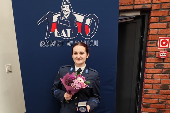 zdjęcie przedstawia policjantkę z medalem i kwiatami