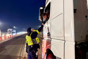 zdjęcie przedstawia policjanta w trakcie kontroli trzeźwości kierującego samochodem.