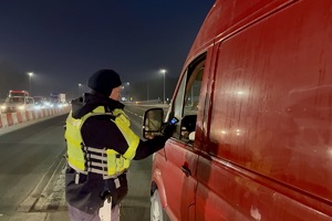 zdjęcie przedstawia policjanta w trakcie kontroli trzeźwości kierującego samochodem.