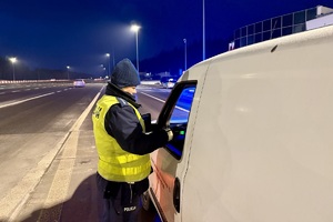 zdjęcie przedstawia policjanta w trakcie kontroli trzeźwości kierującego samochodem.