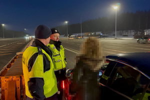 zdjęcie przedstawia policjanta w trakcie kontroli trzeźwości kierującego samochodem.