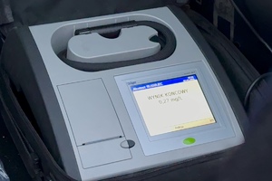 zdjęcie przedstawia policjanta w trakcie kontroli trzeźwości kierującego samochodem.