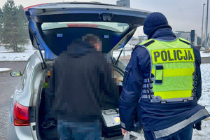 zdjęcie przedstawia policjanta w trakcie kontroli trzeźwości kierującego samochodem.