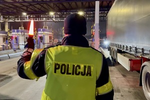 zdjęcie przedstawia policjanta w trakcie kontroli trzeźwości kierującego samochodem.