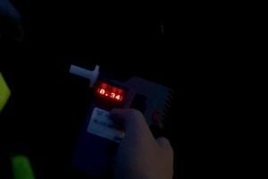 zdjęcie przedstawia policjanta w trakcie kontroli trzeźwości kierującego samochodem.