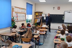 na zdjęciu widoczny policjant w trakcie prelekcji dla dzieci w klasie szkolnej