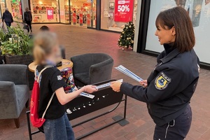 zdjęcie przedstawia policjantkę wręczającą odblaski wolontariuszowi