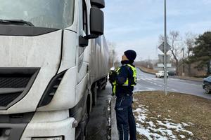 na zdjęciu policjant zatrzymuje do kontroli ciężarówkę