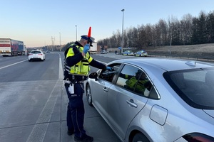 zdjęcie przedstawia policjanta w trakcie kontroli trzeźwości kierującego.