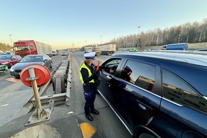 zdjęcie przedstawia policjanta w trakcie kontroli trzeźwości kierującego.