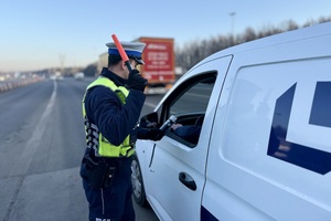 zdjęcie przedstawia policjanta w trakcie kontroli trzeźwości kierującego.