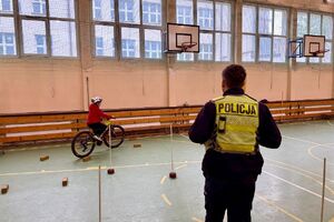policjant w trakcie egzaminu praktycznego na kartę rowerową obserwuje przejazd dziecka na rowerze.