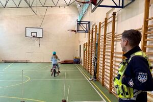 policjant w trakcie egzaminu praktycznego na kartę rowerową obserwuje przejazd dziecka na rowerze.
