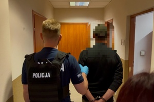 sprawca kradzieży prowadzony korytarzem przez policjanta